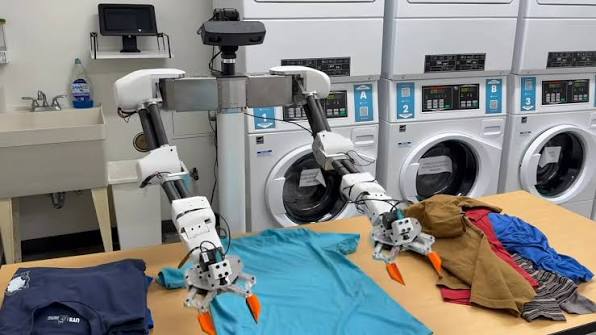 Isaac the robot folding laundry inside a laundry room.